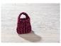 Sac à main bordeaux tricoté à la main sur fond de bois blanc.