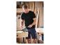 T-shirt noir et shorts de travail en jean : un homme travaille dans son atelier.
