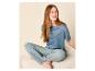 Femme en haut de pyjama bleu et pantalon rayé assise sur un canapé.