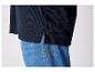 Un pull bleu foncé avec une fente au bas, porté sur un jean bleu.