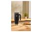 Mug thermique noir avec paille et gaufres sur une table en bois.
