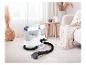Nettoyeur de tapis avec tuyau et buse sur un tapis clair dans un salon confortable.