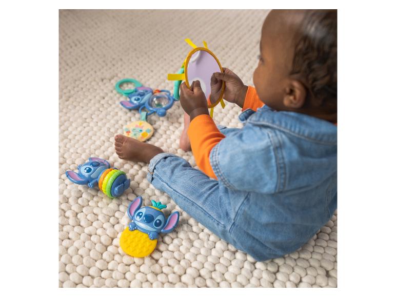 Bébé jouant avec des jouets de personnages de dessins animés et un miroir sur un tapis.