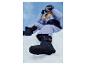 Une personne en combinaison de ski violette et noire, avec des lunettes de ski, assise dans la neige.