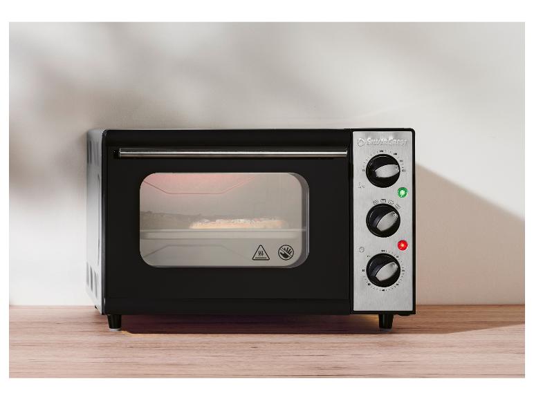 Mini-four SilverCrest noir avec panneau de commande en acier inoxydable sur une table en bois.