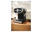 Machine à expresso noire et argentée sur un comptoir en bois avec des grains de café.