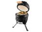 Barbecue kamado noir ouvert avec viande et brochettes de légumes sur la grille.