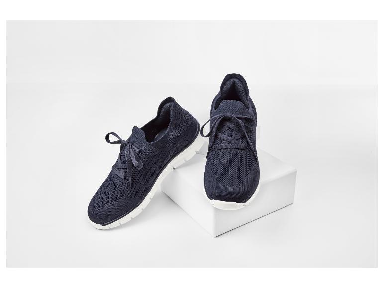 Une paire de chaussures de sport bleu marine avec des semelles blanches sur fond blanc.