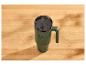 Mug thermique vert avec anse et paille sur une table en bois.