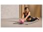 Une femme fait des exercices avec un ballon de fitness rose Crivit sur un tapis de yoga.