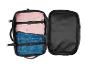 Une valise noire ouverte avec une chemise rose et un jean bleu.