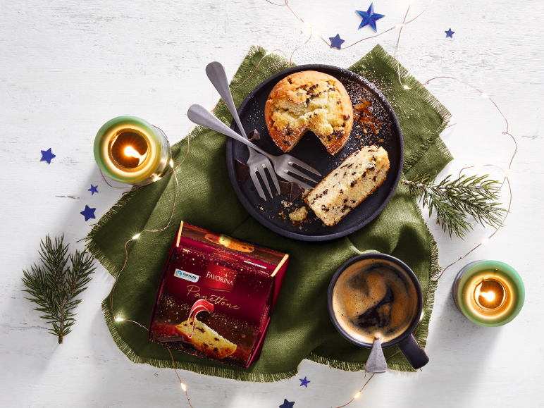 Panettone aux pépites de chocolat, café et bougies dans une ambiance festive.