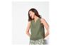 Femme en débardeur vert et short à motifs, riant et regardant vers la gauche.