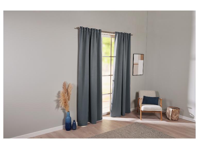 Des rideaux gris pour une fenêtre avec un fauteuil et un tapis.