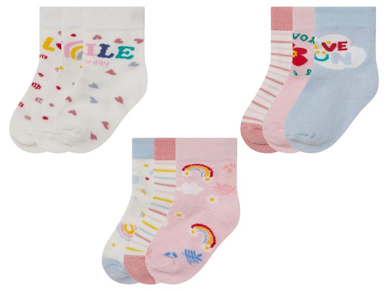 Un ensemble de trois paires de chaussettes pour enfants avec des motifs arc-en-ciel, cœurs et rayures.