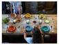 Table en bois dressée avec des assiettes colorées, des couverts et des bougies, prête pour un repas.