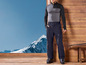 Un homme porte des vêtements de ski, dont un pantalon noir et un pull thermique gris.