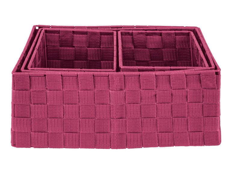 Trois paniers de rangement tissés roses.