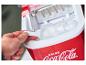 Une main prend des glaçons dans une machine à glaçons Coca-Cola rouge.