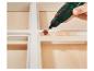 Outil rotatif avec accessoire de ponçage sur bois peint en blanc.
