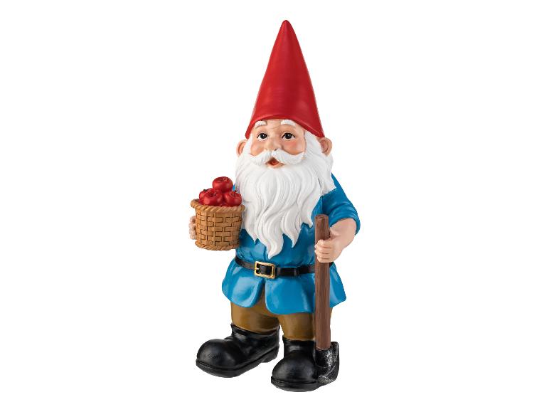 Un gnome de jardin avec un panier plein de pommes et une pelle.