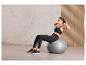 Une femme fait des exercices abdominaux sur un ballon de fitness gris de Crivit.
