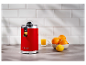 Presse-agrumes rouge rétro 1973 avec des oranges et du jus.