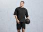 Un homme portant un t-shirt et un short noirs tient un ballon de médecine.