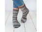 Pieds portant des chaussettes en laine grises et des jeans bleus sur un plancher en bois blanc.