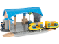 Gare de jouet avec un train jaune et une figurine de contrôleur.
