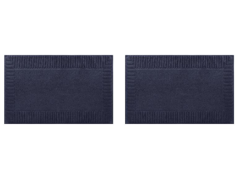 Deux tapis de bain bleu marine avec un motif de bordure texturé.