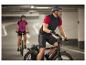 Deux cyclistes sur vélos électriques dans un parking.