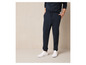 Homme portant un pantalon de survêtement bleu et des baskets Vans blanches.
