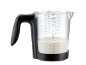 Pichet doseur avec du lait, avec des mesures en ml et en tasses.