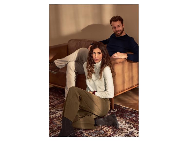 Couple détendu sur canapé et tapis, portant des pulls et des pantalons décontractés.