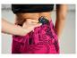Une femme avec un smartphone dans la poche de son pantalon à rayures roses et noires.