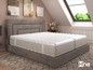 Un cadre de lit gris avec un matelas blanc et un tapis à motif géométrique.