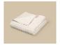 Couverture matelassée de couleur crème pliée sur un fond beige.