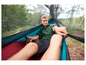 Un homme se relaxe dans un hamac avec moustiquaire dans la forêt.