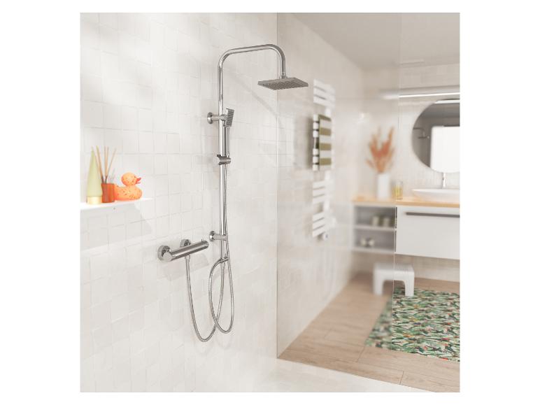 Ensemble de douche chromé avec pommeau de douche pluie et douchette, sur carrelage blanc dans la salle de bain.