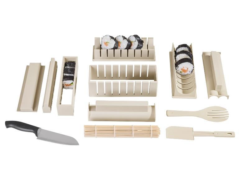 Kit de fabrication de sushis avec moules, natte en bambou, couteau et ustensiles, avec sushis préparés.
