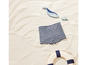 Un maillot de bain rayé sur le sable avec une bouée de sauvetage et des jouets en bois.