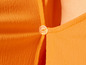 Gros plan sur une chemise orange avec un bouton.