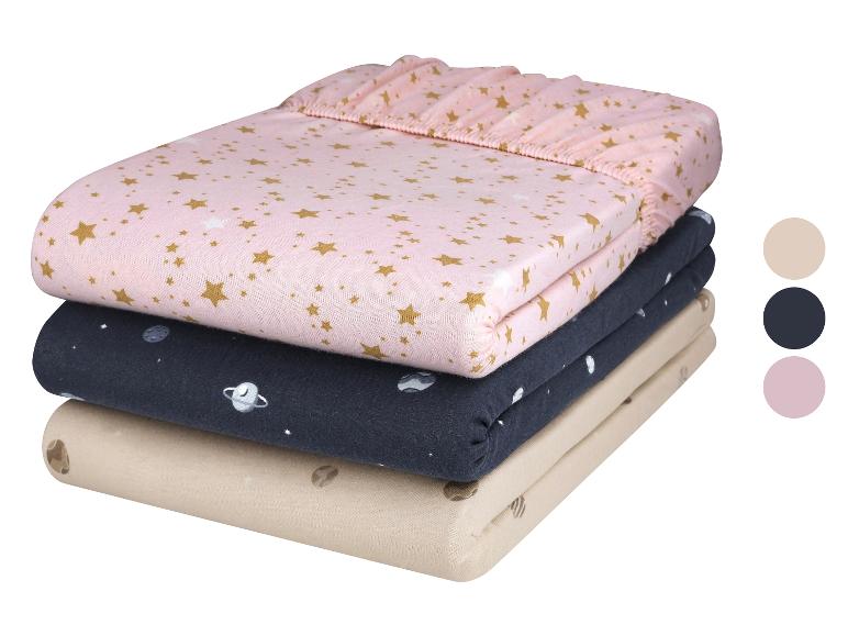Trois draps de coton pour berceau avec des imprimés étoiles et planètes.