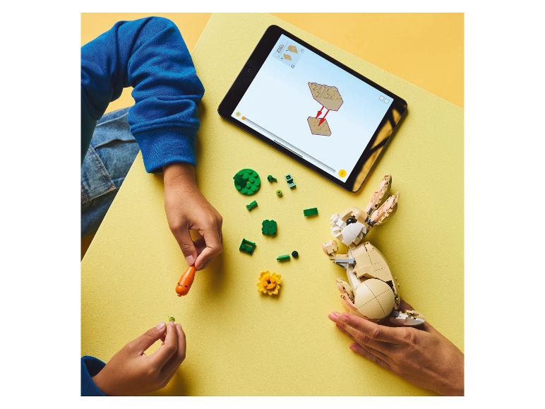 Enfant et adulte construisent un lapin LEGO avec des instructions numériques sur une tablette.