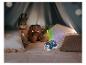 Un projecteur de veilleuse en forme de phoque bleu illumine une tente avec des peluches.