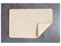 Un tapis de bain beige à motif en losanges sur un sol en carreaux gris.