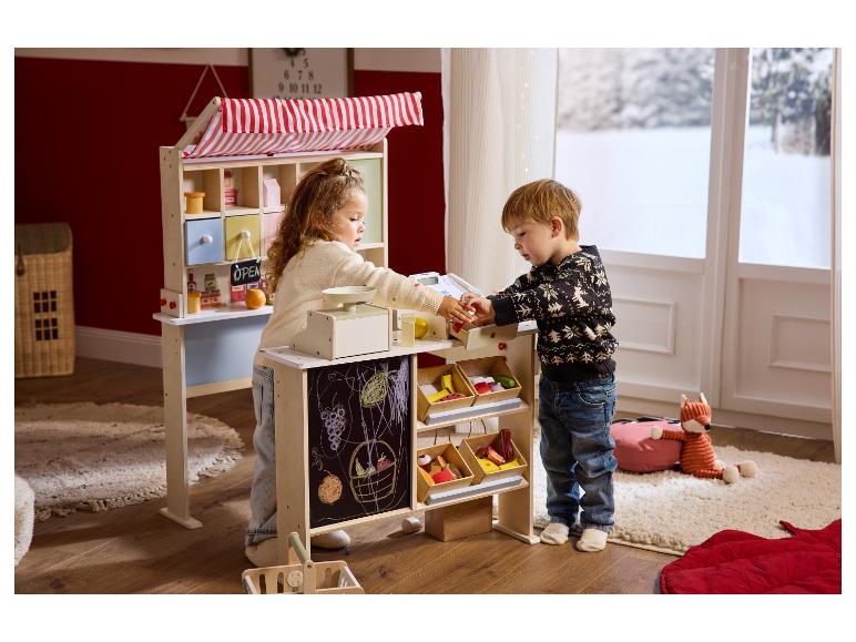 Deux enfants jouent avec un étal de marché en bois et une caisse enregistreuse.