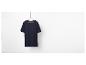 Un t-shirt bleu marine suspendu à un cintre en bois.