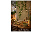 Une table avec une salade, une pizza et des boissons, éclairée par des lampes avec des abat-jour en verre.